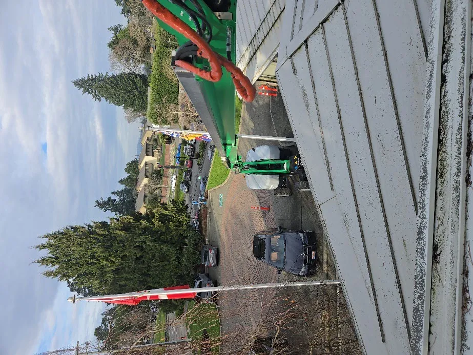 Overhead photo of a green cherry picker lift positioned next to the Town Hall roof for inspections