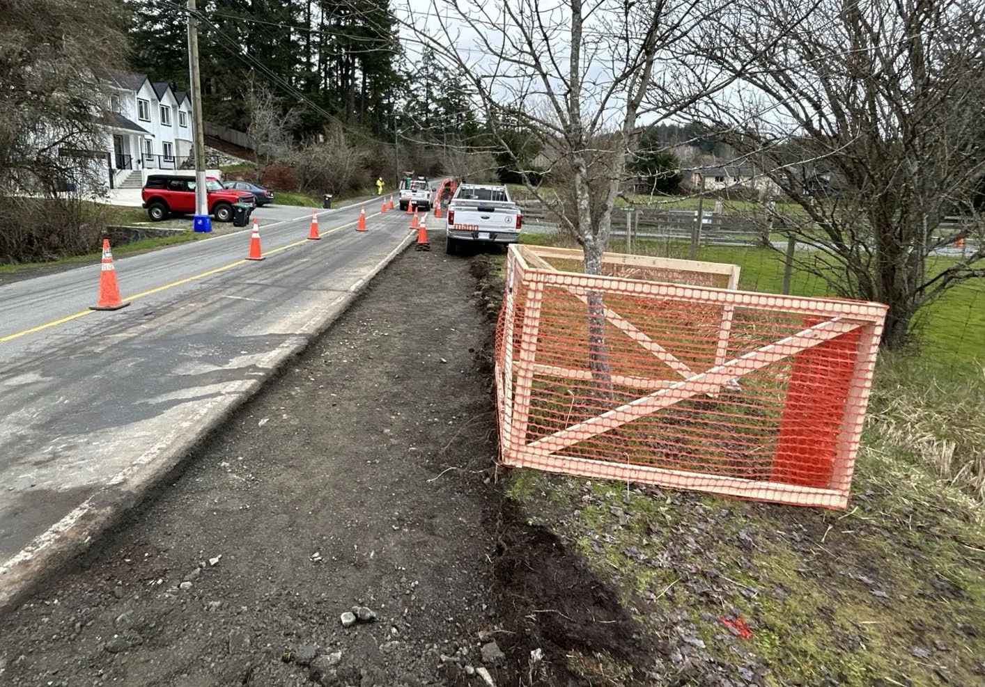 Photo showing site preparation for the Atkins Road Sidewalk Project with tree protection fencing along a road
