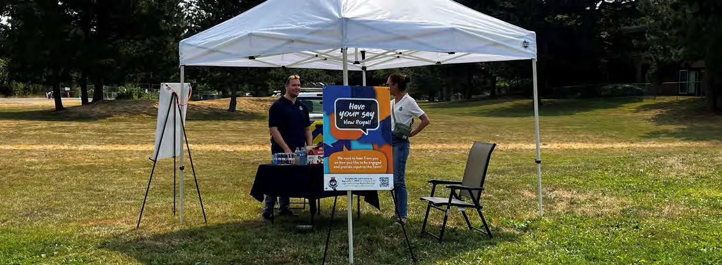 Town representatives interacting with residents at a community engagement tent in a park