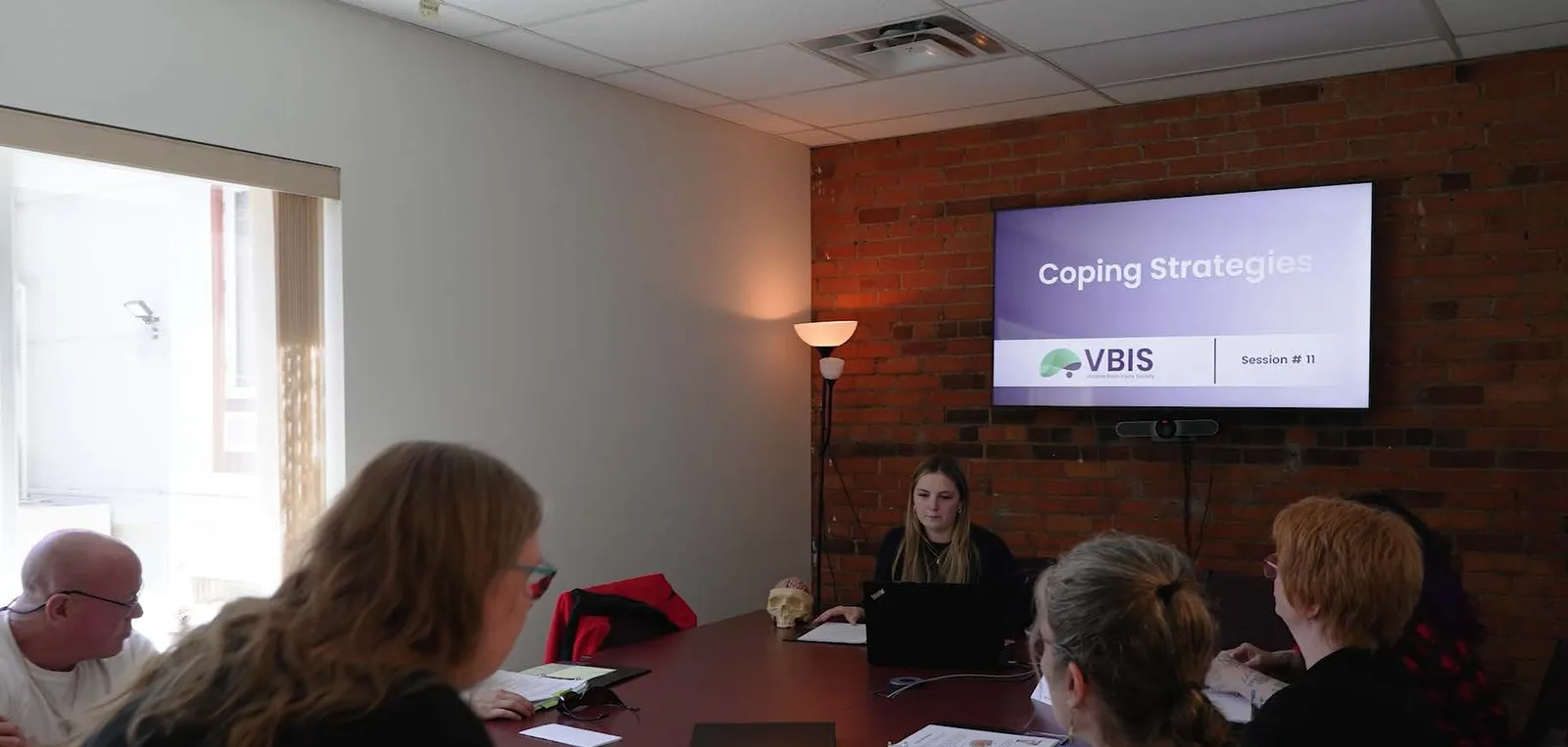 People in a meeting room watching a presentation on "Coping Strategies"