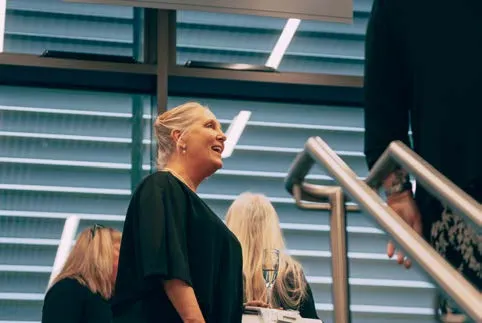 Two women at an event, one speaking and one listening