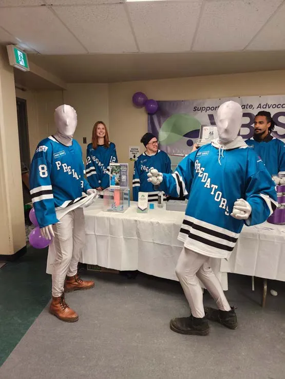 Group of people wearing hockey jerseys standing behind an information table