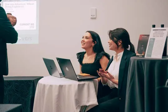 Two women working with laptops at a gala event