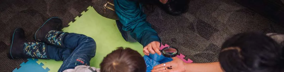 Children leaning over a blue tarp to examine soil