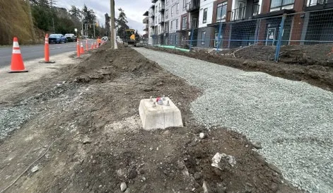 Road construction progress on Burnside Road West showing new curbing and sidewalk preparation