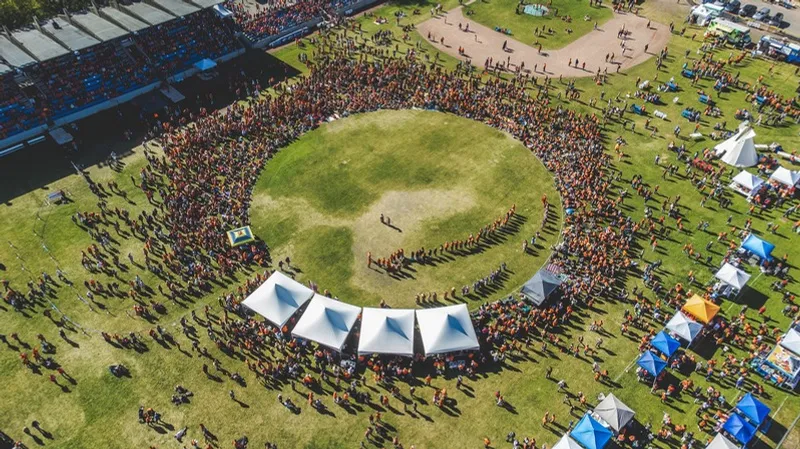 Aerial view of thousands of attendees forming a large circle around a grass field