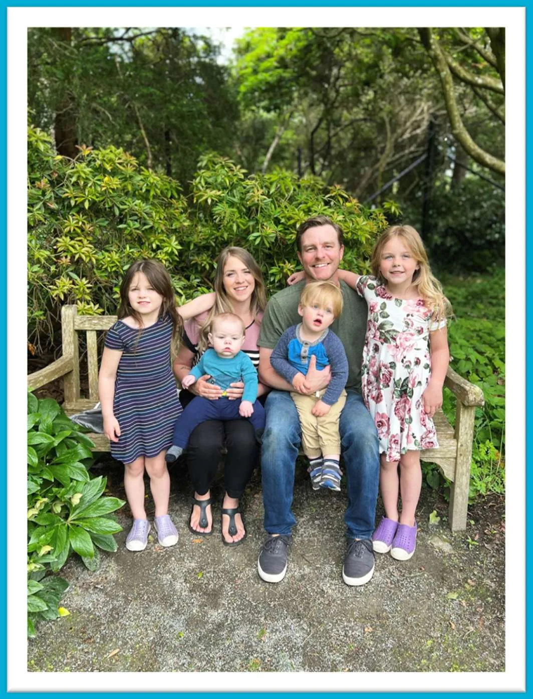 A family of six sitting together on an outdoor wooden bench