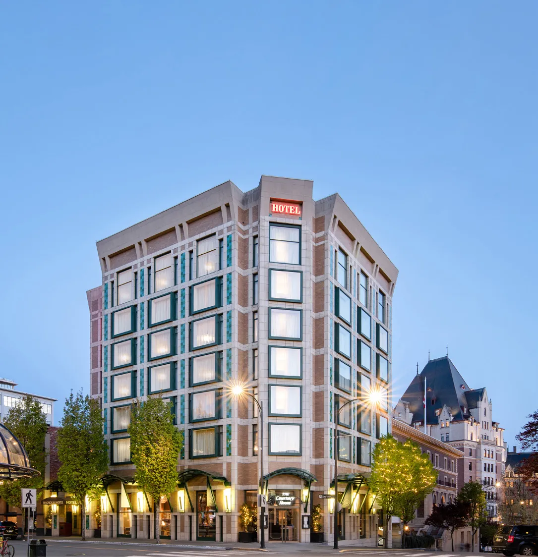 A modern multi-story hotel building at twilight, with a bright "HOTEL" sign on the roof