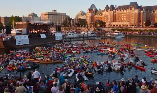 A vast fleet of kayaks and boats gathered in the harbor for an event at dusk