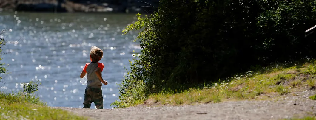 Child running along a path next to a body of water.