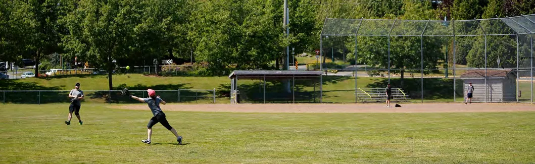 People playing softball on a grassy field.