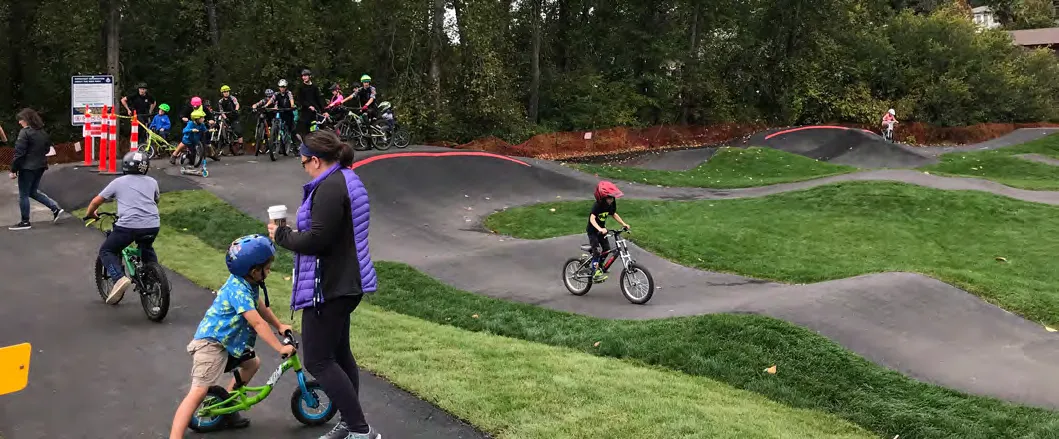 Children riding bikes on a paved pump track.
