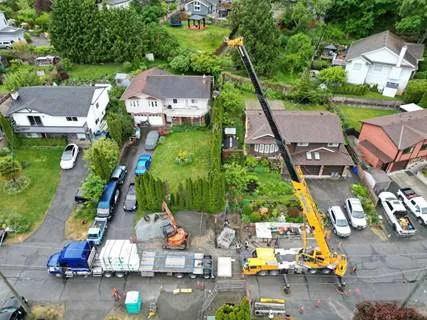 Aerial view of a road closure with a crane and trucks for the installation of a mechanical valve chamber