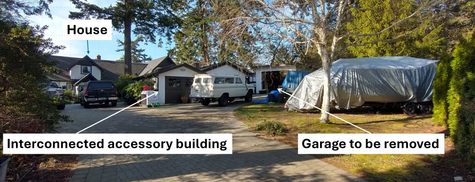 Photograph of the property from the driveway showing the main house, an interconnected accessory building, and the garage to be removed