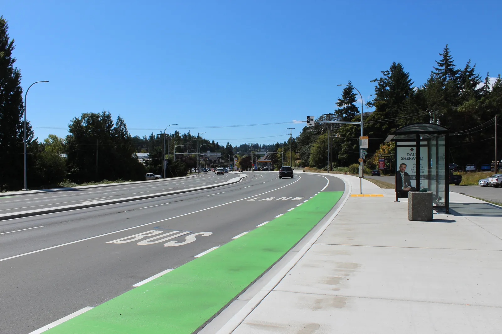 Photo of a modern roadway with a dedicated green bus/bike lane and a bus stop shelter