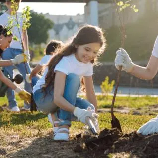 Two children planting a tree sapling in a park setting