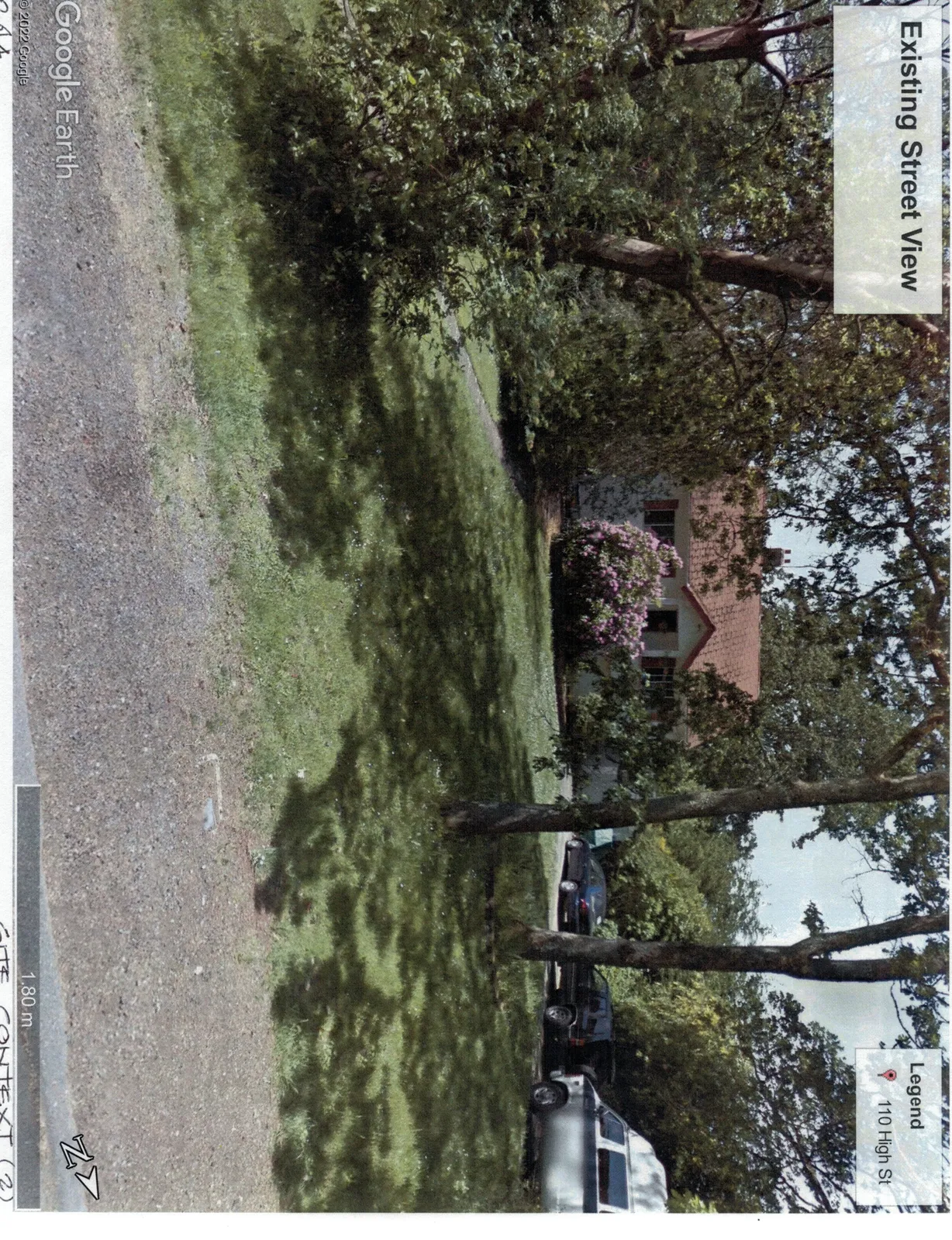 Street view photograph of 110 High St showing a small white cottage with a red roof, a large pink flowering bush, and several vehicles parked on a gravel driveway.