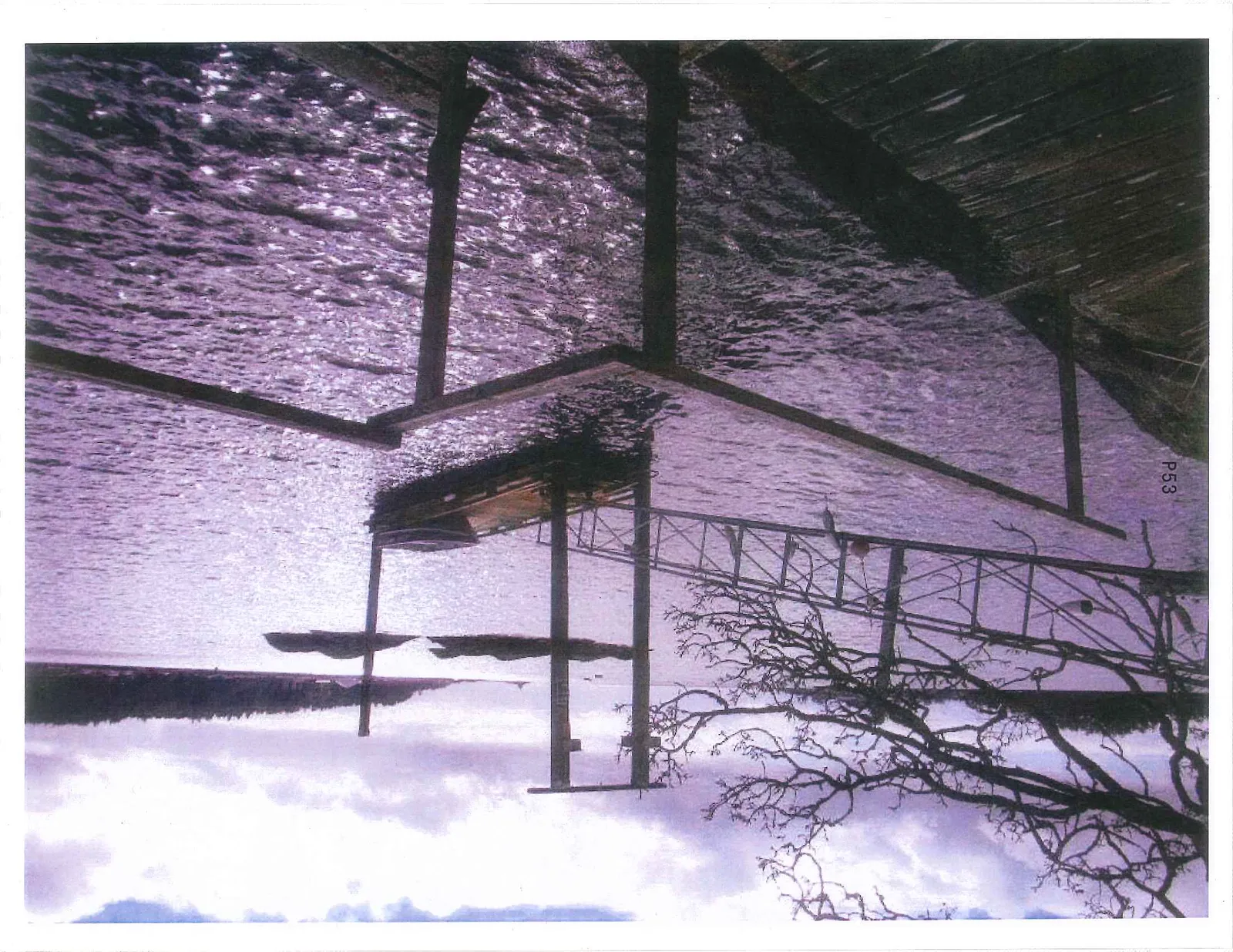 A view from an elevated position looking down at a wooden dock and a metal gangway structure over the water.