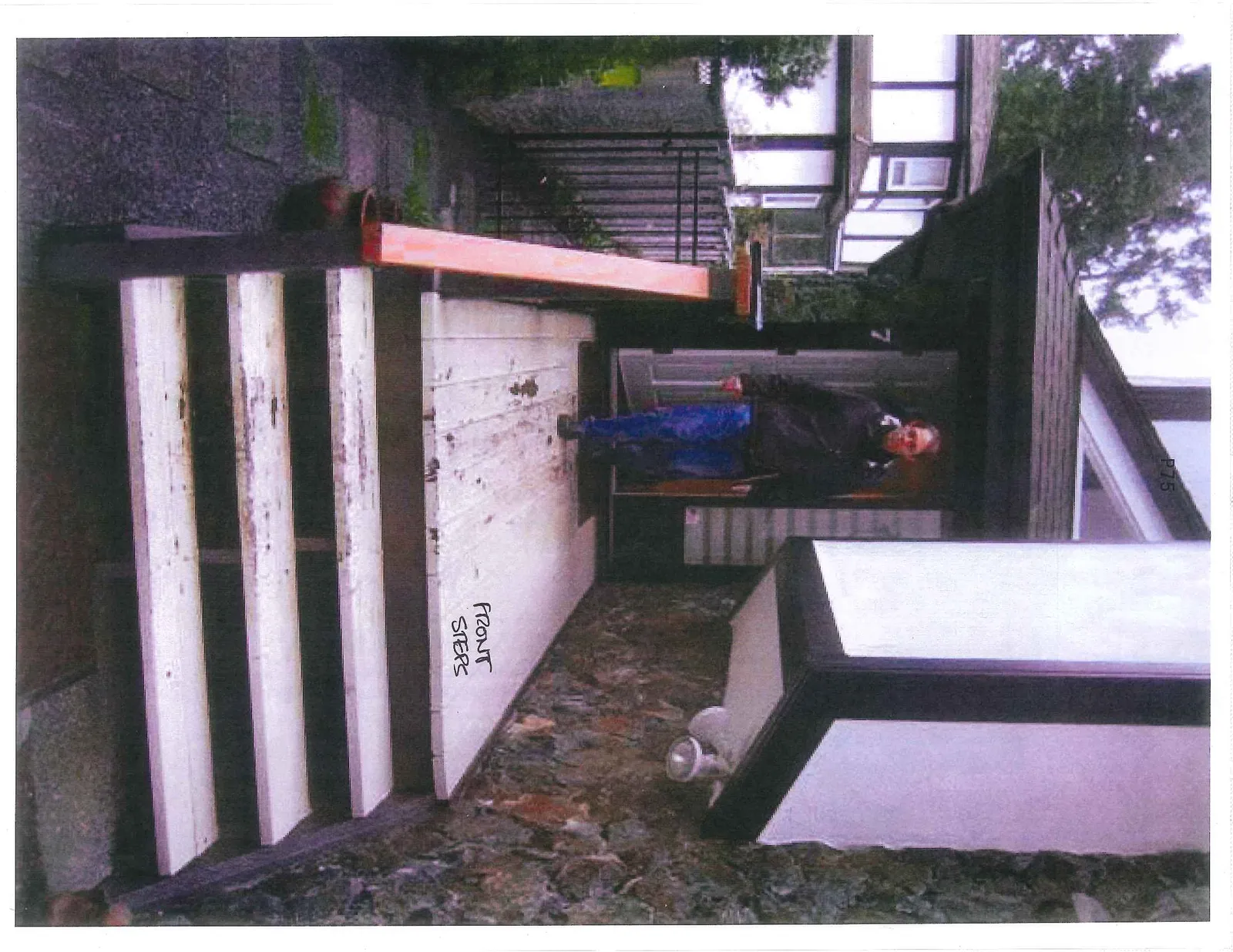 Front view of the entrance to house number 7, showing a person at the door and the white-painted steps leading to the porch
