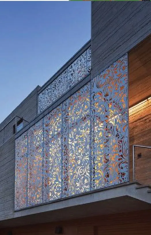 Photograph of a decorative laser-cut metal privacy screen installed on a building exterior