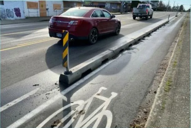 Photograph showing an example of a protected bike lane separated by a concrete physical barrier and bollards