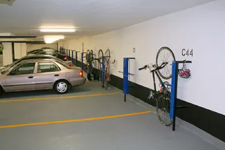 Bicycle mounted on wall-rack in a parking garage adjacent to a car