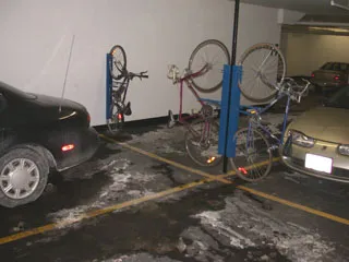 Bicycles mounted on vertical racks positioned between parked cars