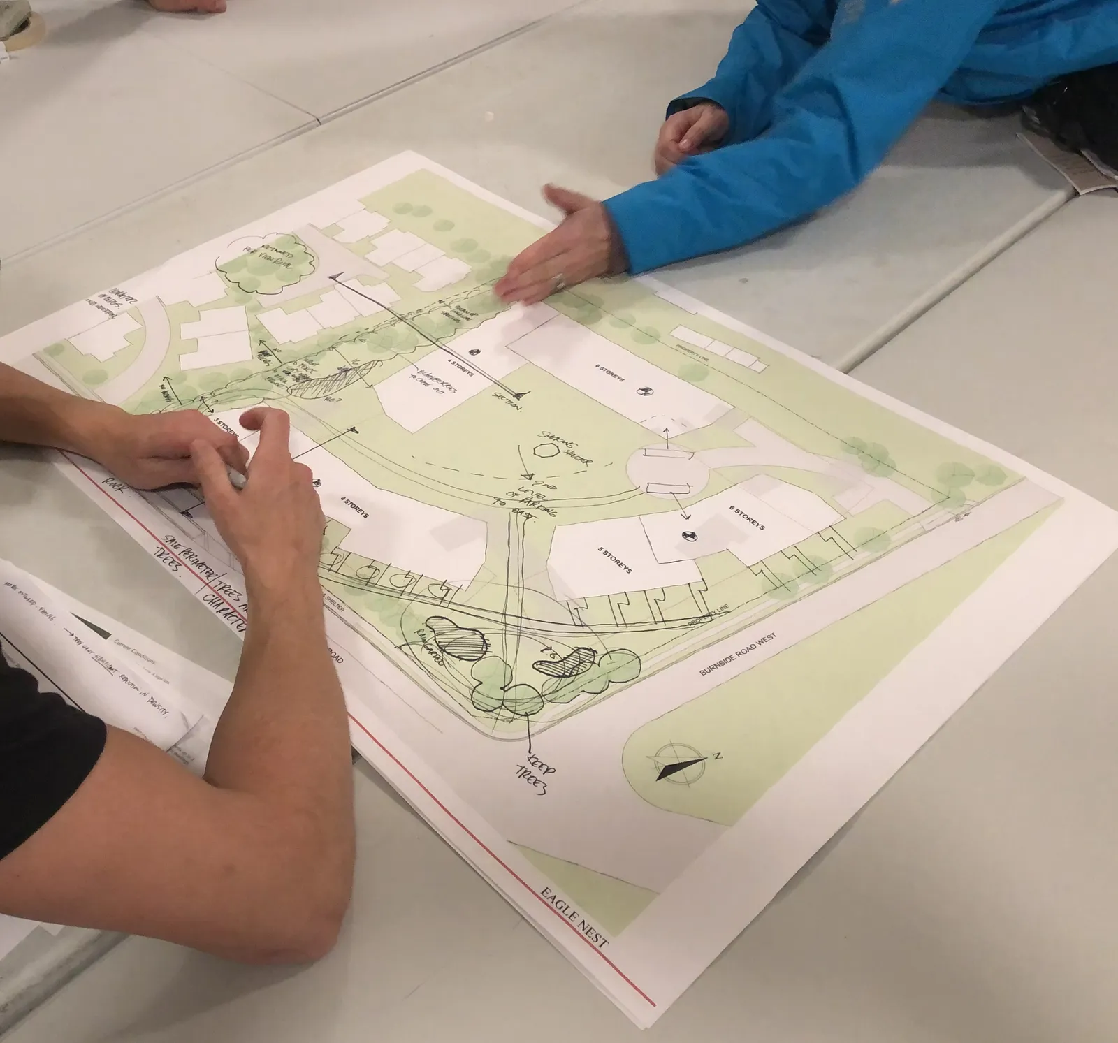 Photograph of a community engagement workshop session showing people reviewing a large site plan