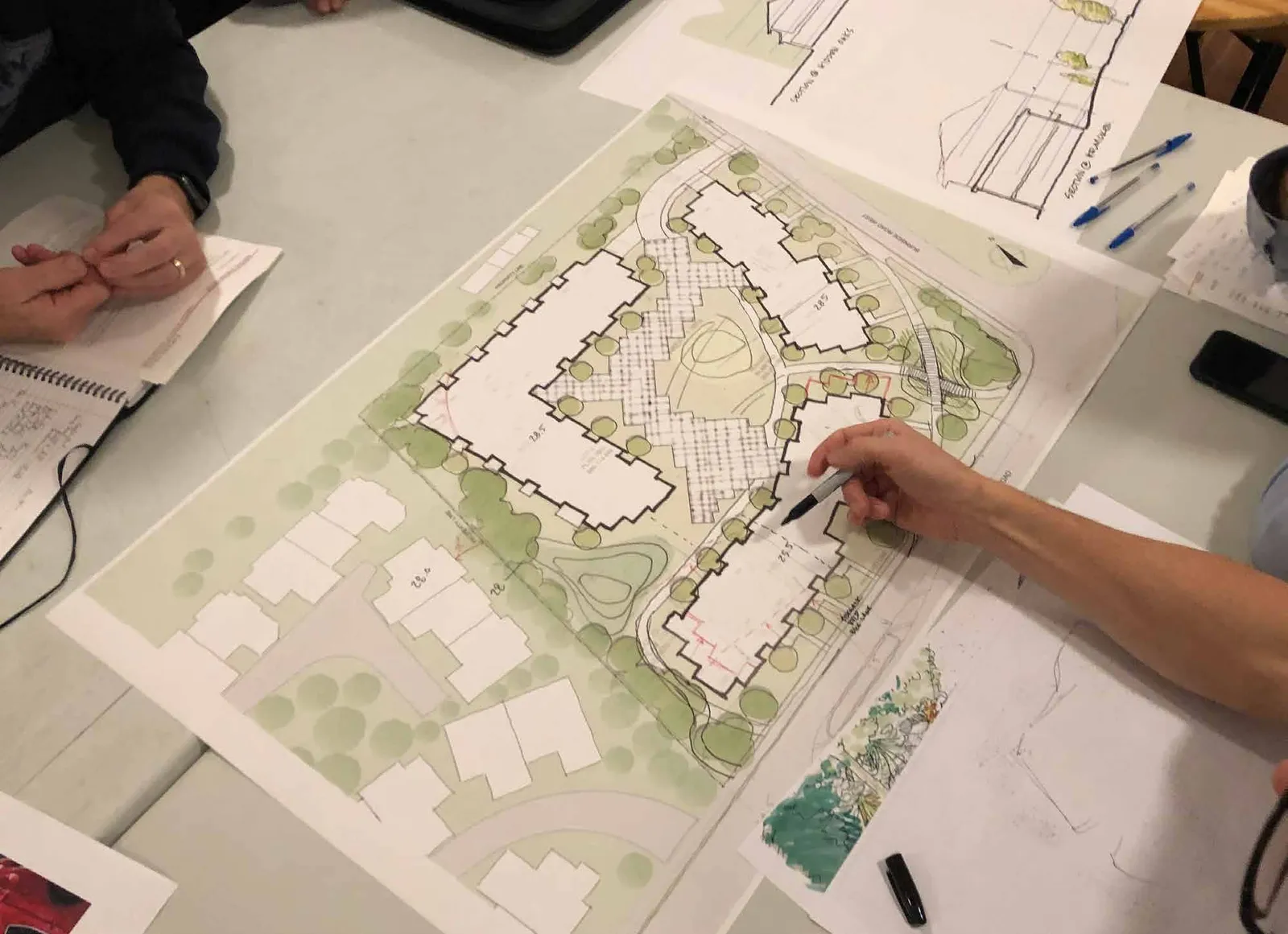 Photograph showing people collaborating around a large-scale architectural site plan on a table