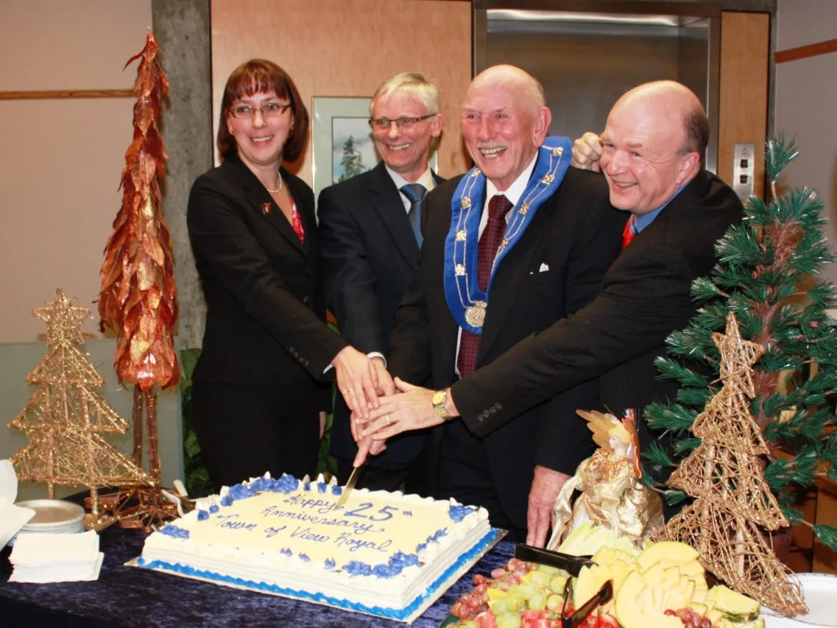 Four people in formal attire, including the Mayor in ceremonial chains, cutting a cake for the 25th Anniversary.