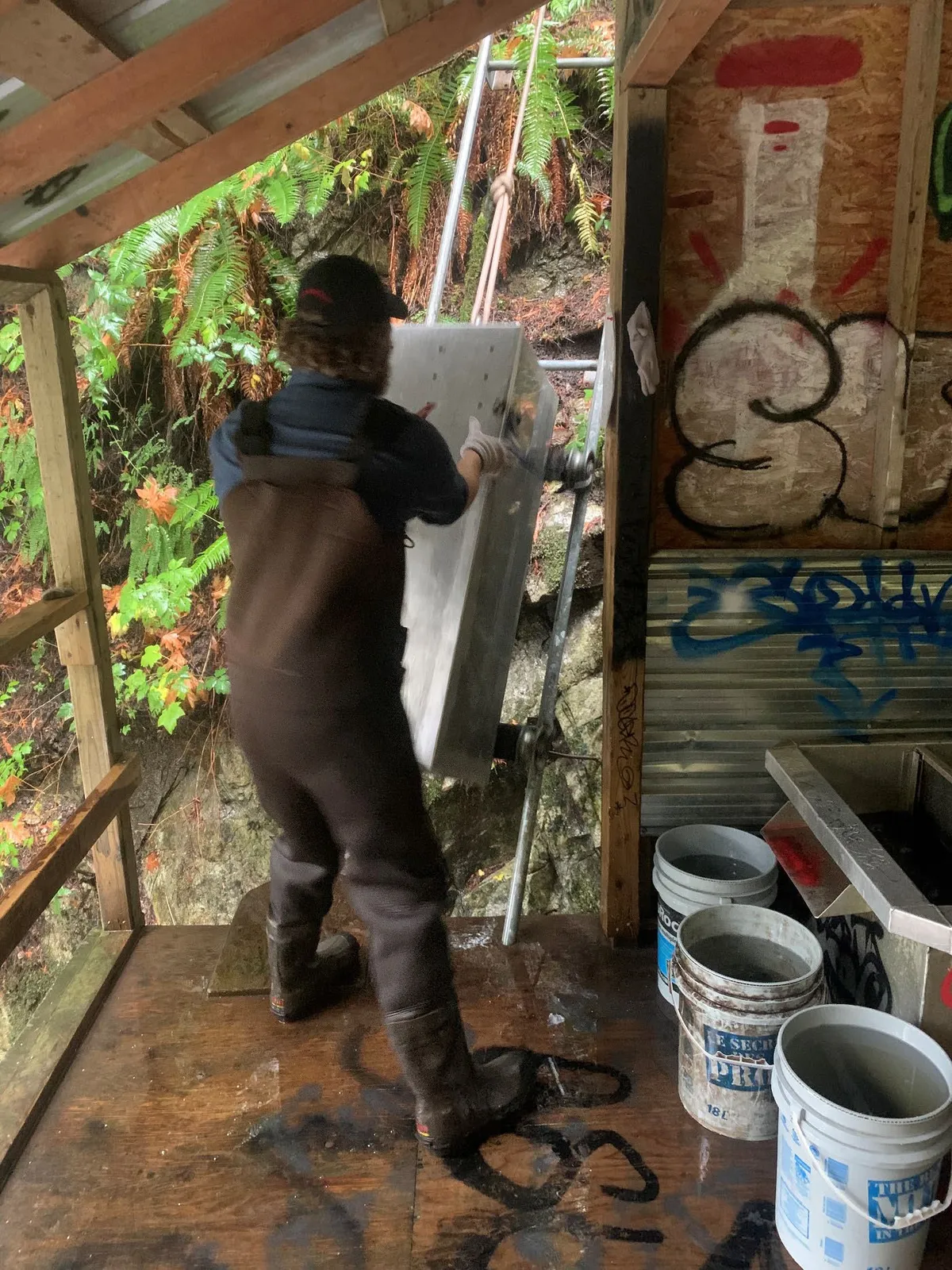 Brad closing the lid of the metal trolley tank inside a wooden structure.