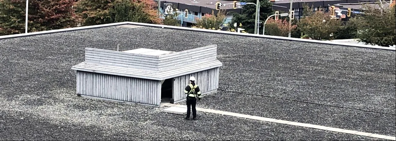 Photograph of a noise reduction screening structure on the building roof with a worker nearby