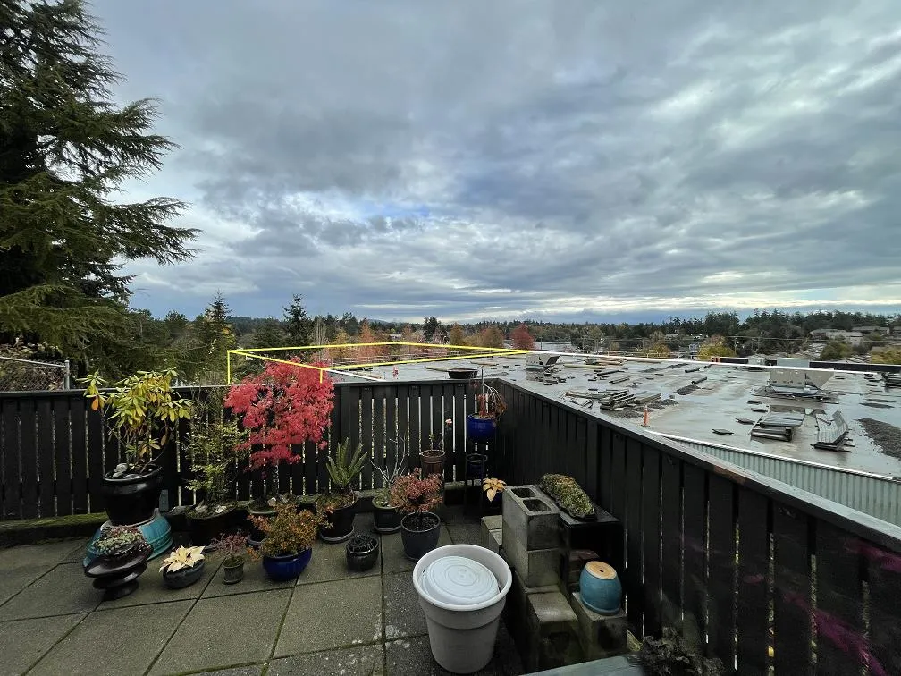 Photo depiction from a main floor balcony showing the proposed building expansion outlined in yellow above the existing rooftop.