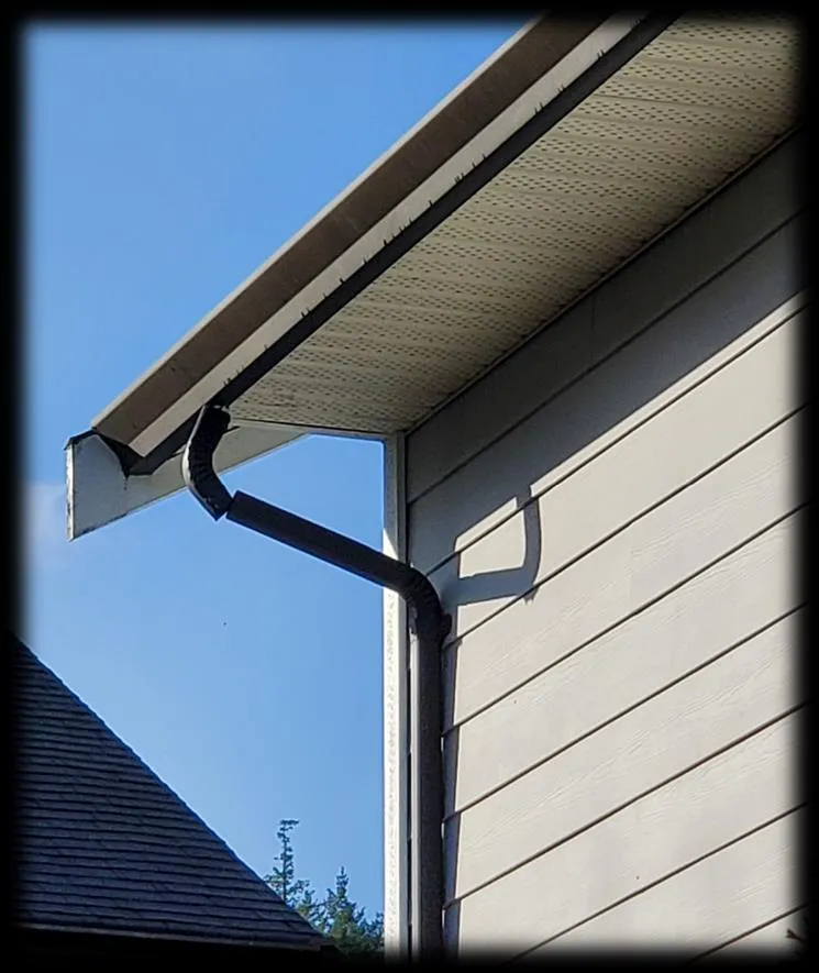 Photograph showing a house corner with gutters and a downspout