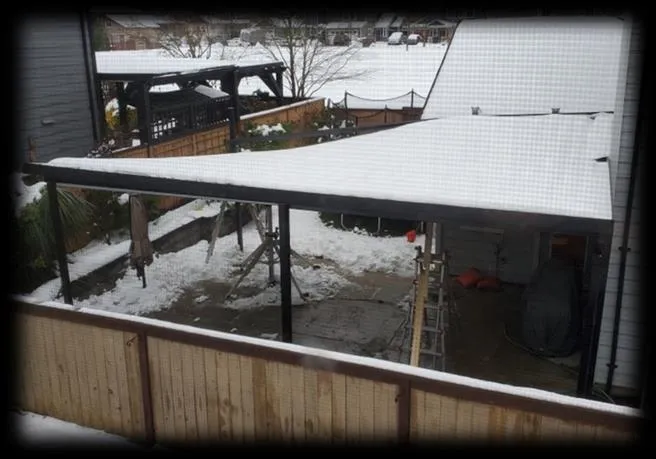 Photograph showing a backyard area with a snow-laden patio cover and surrounding structures