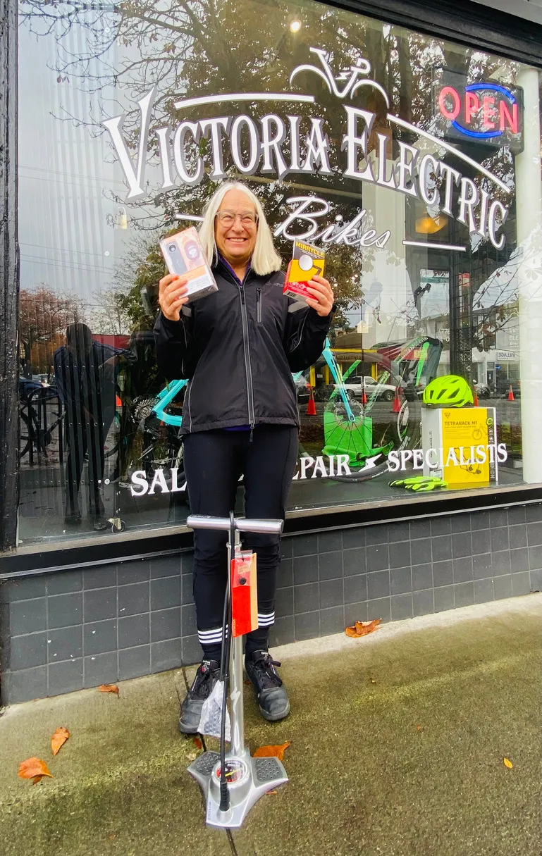 Woman holding prizes in front of Victoria Electric Bikes shop window