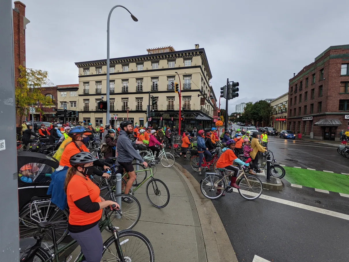 An Indigenous person speaking to a group of cyclists outdoors