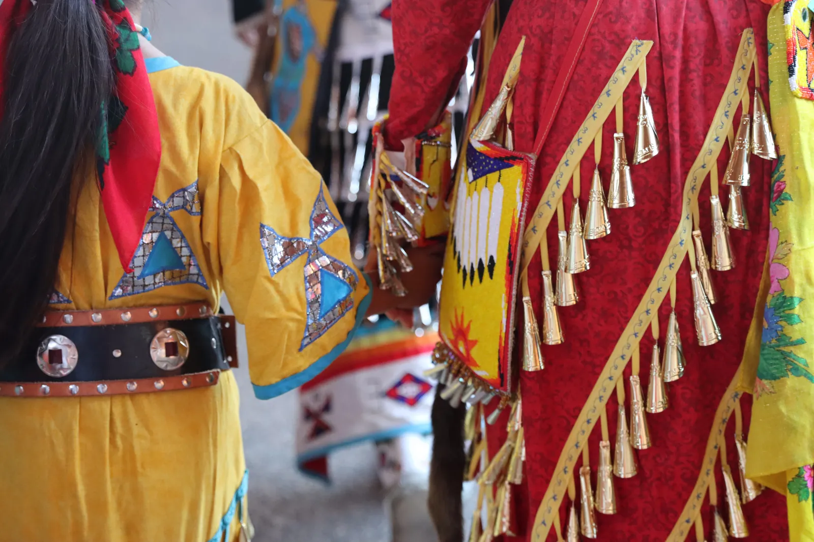 Close-up of traditional Indigenous regalia featuring intricate beadwork and metal jingle cones