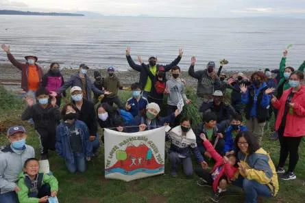 A group of volunteers from the Greater Victoria Green Team posing with tools and a team banner
