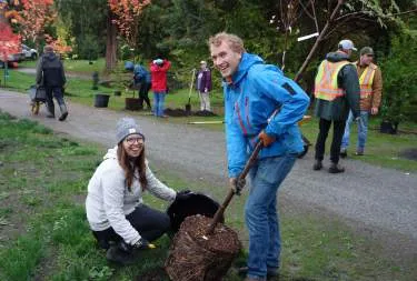 A large group of youth working on a restoration project with shovels and blue tarps