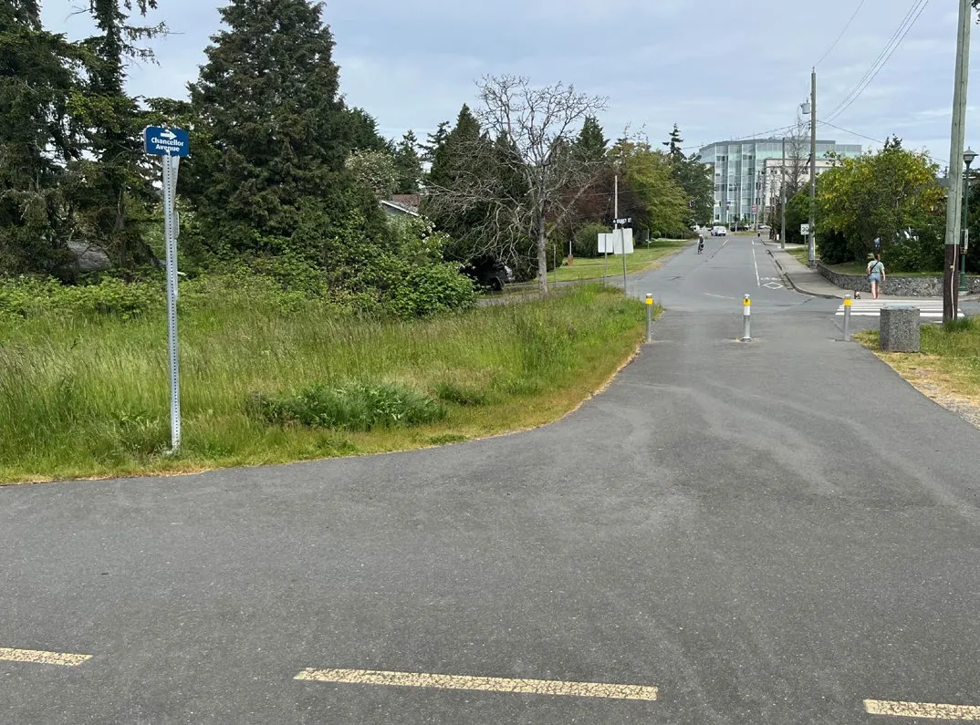 Photo of a paved multi-use trail with a directional sign post