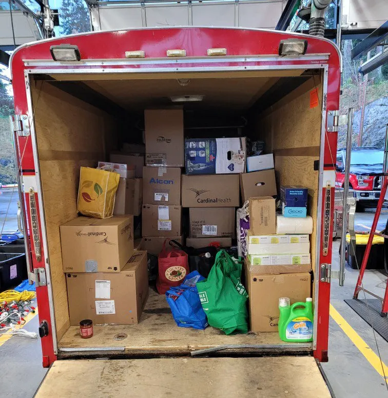 The back of a fire trailer filled with numerous boxes and bags of food donations