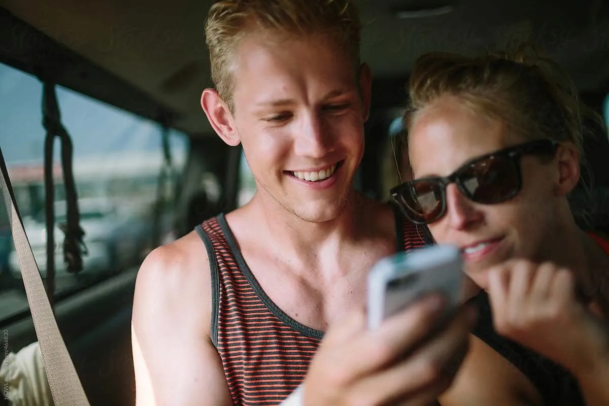 A man and a woman smiling while looking at a smartphone