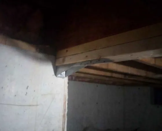 Photograph of underside of floor joists showing packing out requirements at a plumbing penetration, labeled #10