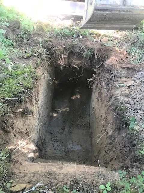 A rectangular soil pit excavated into the ground, showing the vertical soil profile
