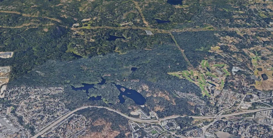 Aerial satellite view of a landscape showing the transition between dense forest and residential developments