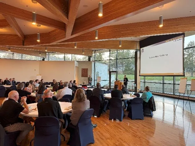 Workshop session with a presentation on a large screen and attendees seated at round tables.