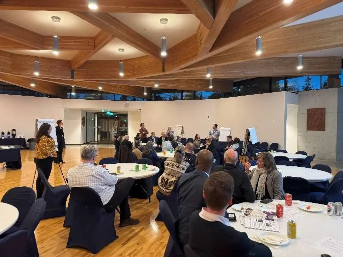 Workshop session showing attendees in discussion at tables with facilitators.