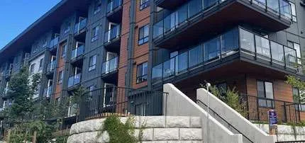 The lower portion of a modern residential building with a grey stone block retaining wall and a concrete staircase leading up to an entrance