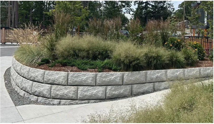Curving concrete block retaining wall with landscaping and an adjacent sidewalk